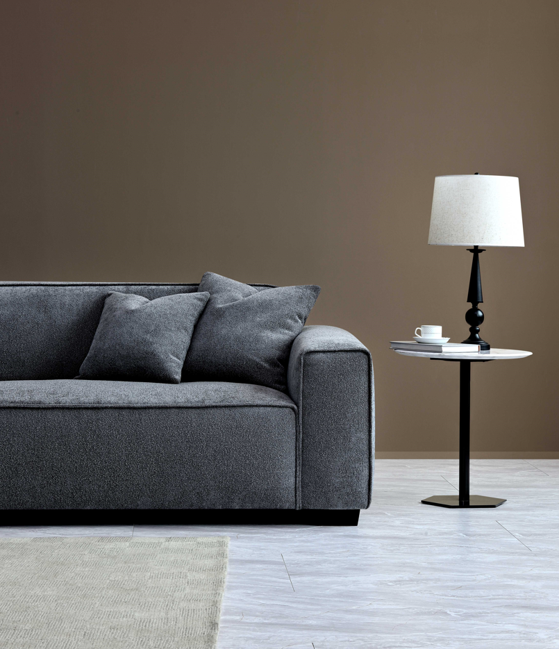 Stylish Aluxo Dakota Sofa Range in Charcoal Boucle, with simple decor and a lamp beside it, creating a cozy atmosphere.
