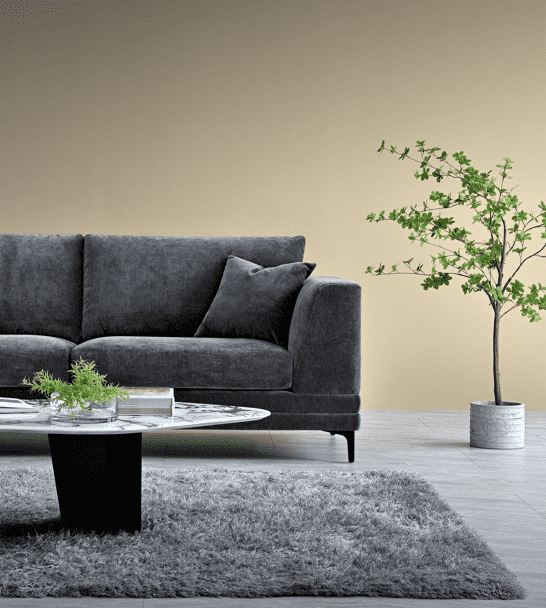 The Aluxo Lenox Sofa Range in Steel Velvet featured in a stylish living room setting with a round coffee table and greenery.