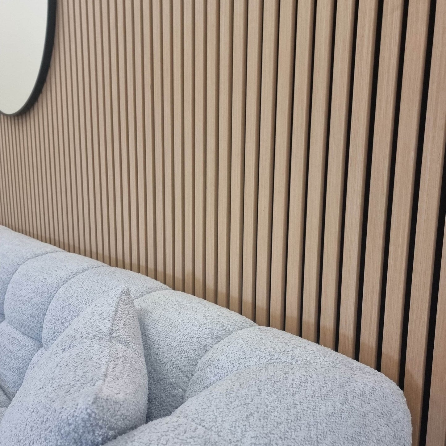 Close-up of Acoustic Wood Slatted Wall Panels by Furnish 365 Limited, framed by a soft grey sofa, emphasizing the chic design of luxury furniture.